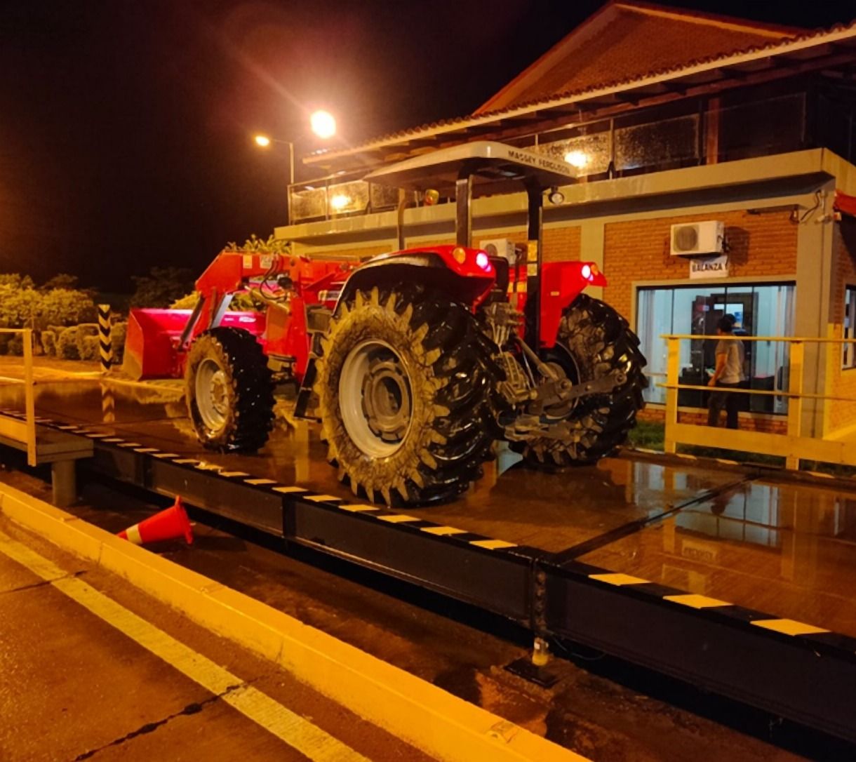 Tractor rojo sobre una plataforma de pesaje, de noche