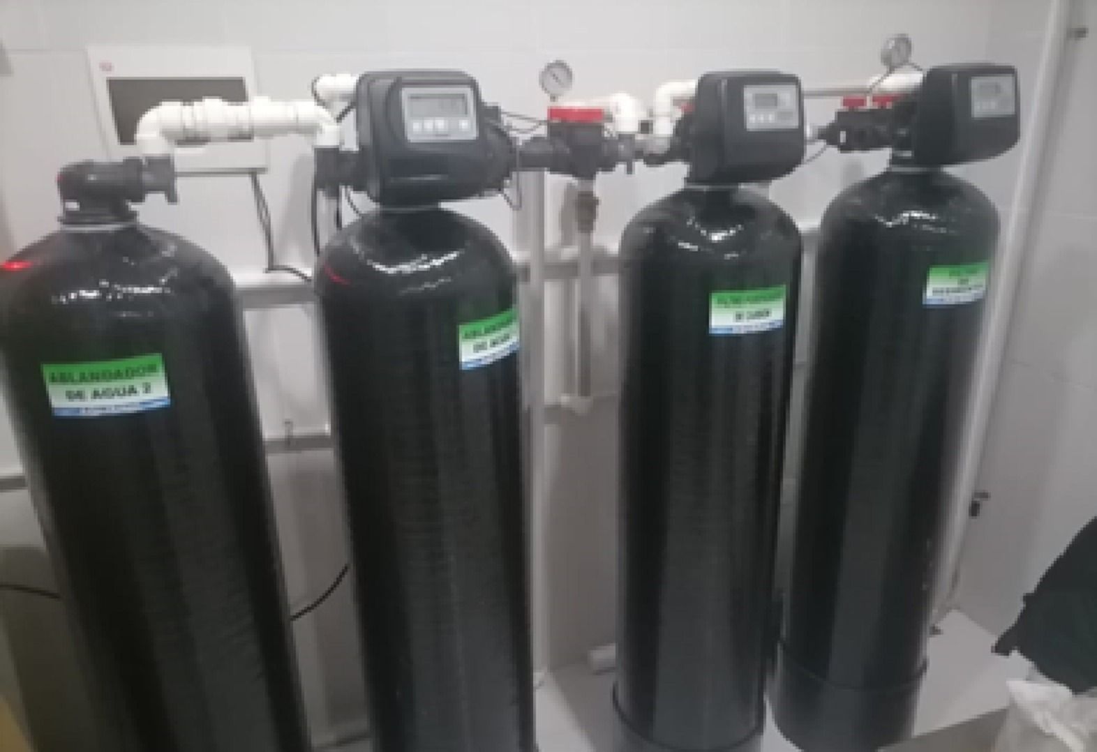 Cuatro tanques de filtros con válvulas de control sobre un piso blanco