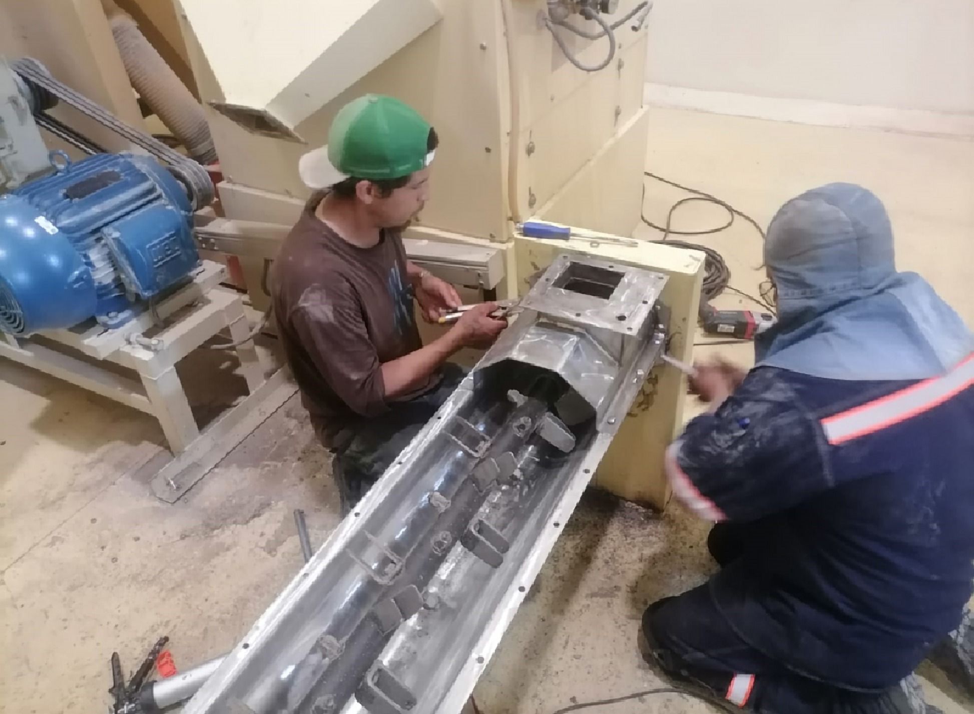 Dos técnicos trabajando en un transportador de tornillo abierto
